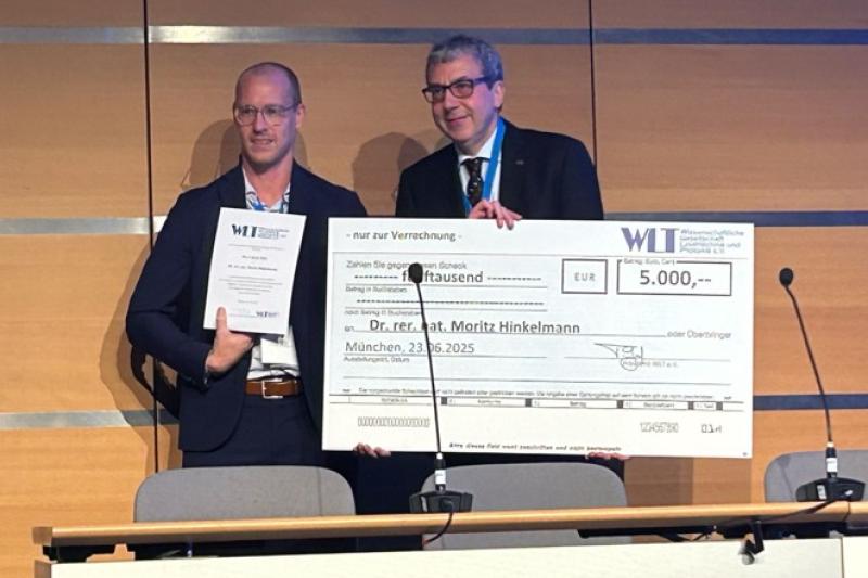 Dr. Moritz Hinkelmann wird ein Check über 5.000 Euro überreicht