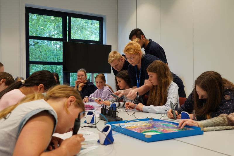 Mehrere Kinder sitzen an einem Tisch und nutzen 3D-Druckstifte.