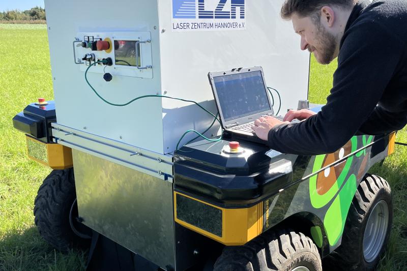 Wissenschaftler arbeitet am Laptop mit Feldroboter.