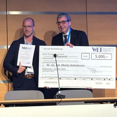 Dr. Moritz Hinkelmann wird ein Check über 5.000 Euro überreicht