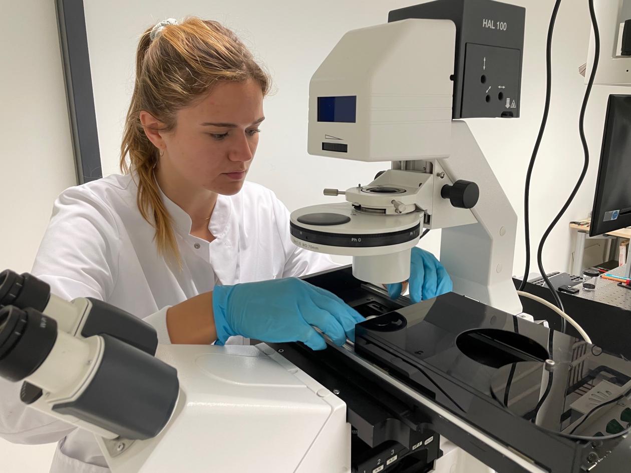 WIssenschaftlerin legt eine Probe in ein Mikroskop ein.