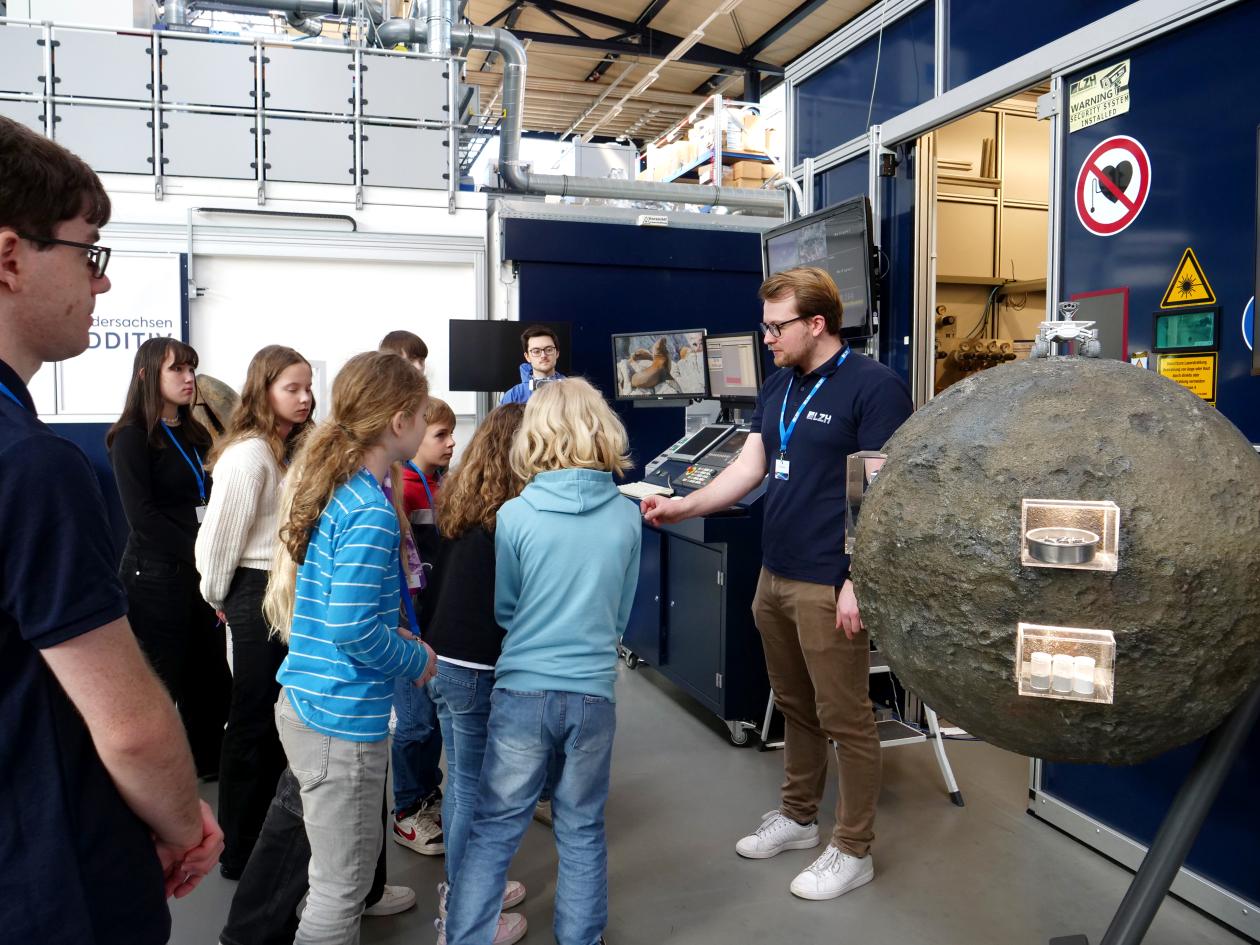 Menschen stehen hinter einem Mond-Exponat