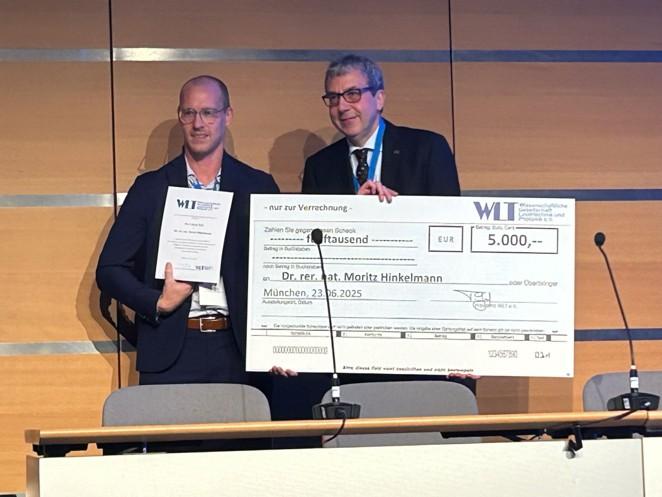 Dr. Moritz Hinkelmann wird ein Check über 5.000 Euro überreicht