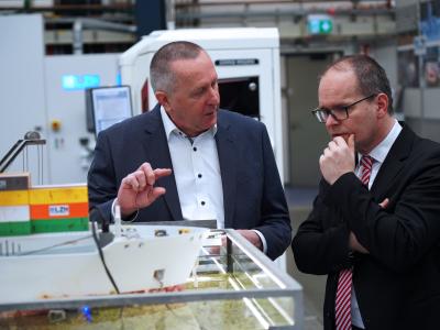 Stefan Kaierle und Minister Tonne vor einen Schiffs-Exponat. 